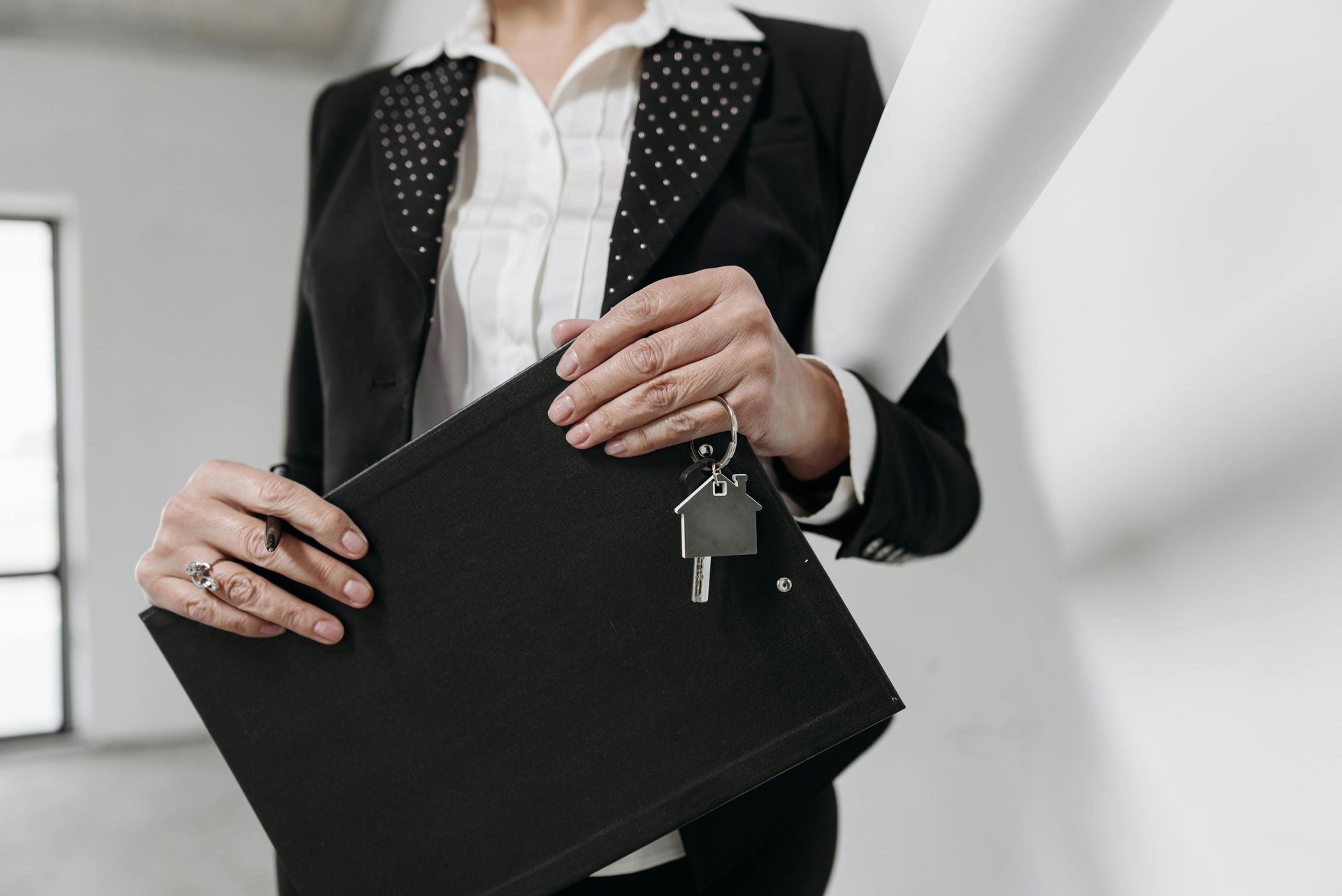 A woman in a suit is holding a clipboard and keys.