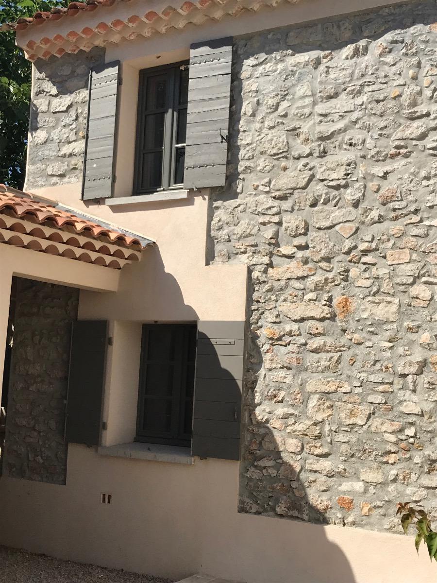 Façade en pierre avec volets gris et toit en tuiles