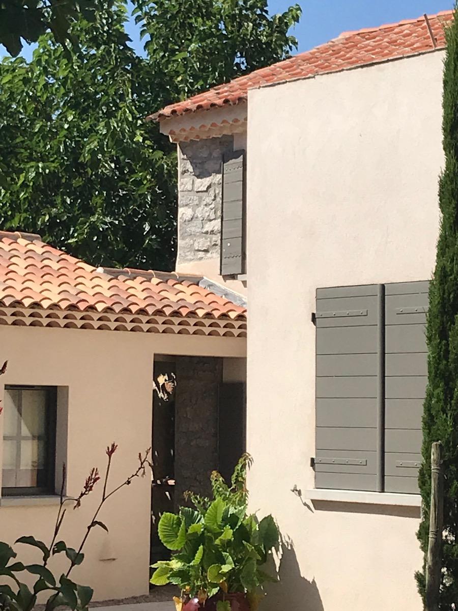 Architecture méditerranéenne avec volets gris et toiture en tuiles