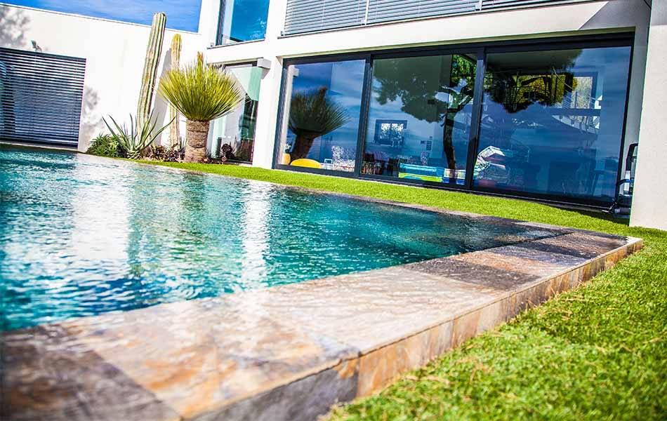 Grande maison moderne avec baie vitrée donnant sur une piscine à débordement