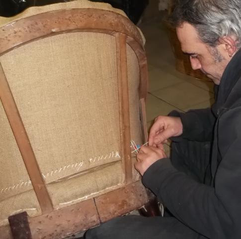 L'artisan coud le bas du dossier