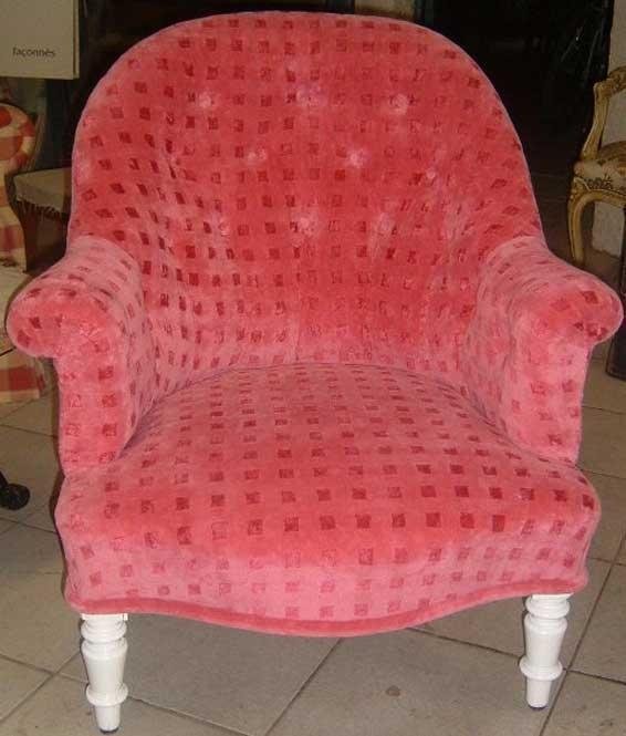Fauteuil rouge avec un tissu duveteux, et des pieds sculptés blancs