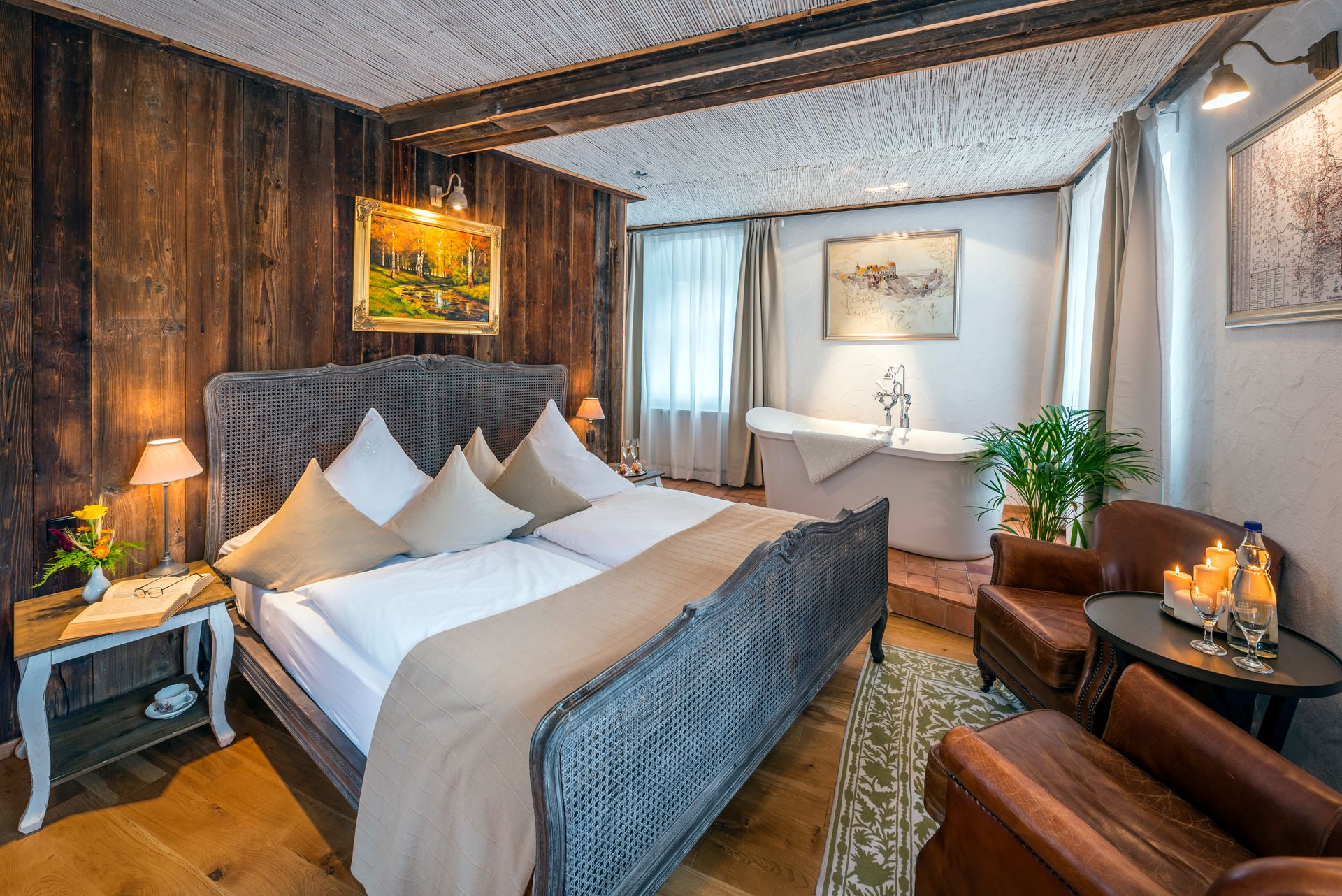 Gemütliches Schlafzimmer mit Holzwänden, Bett, Sessel und freistehender Badewanne.