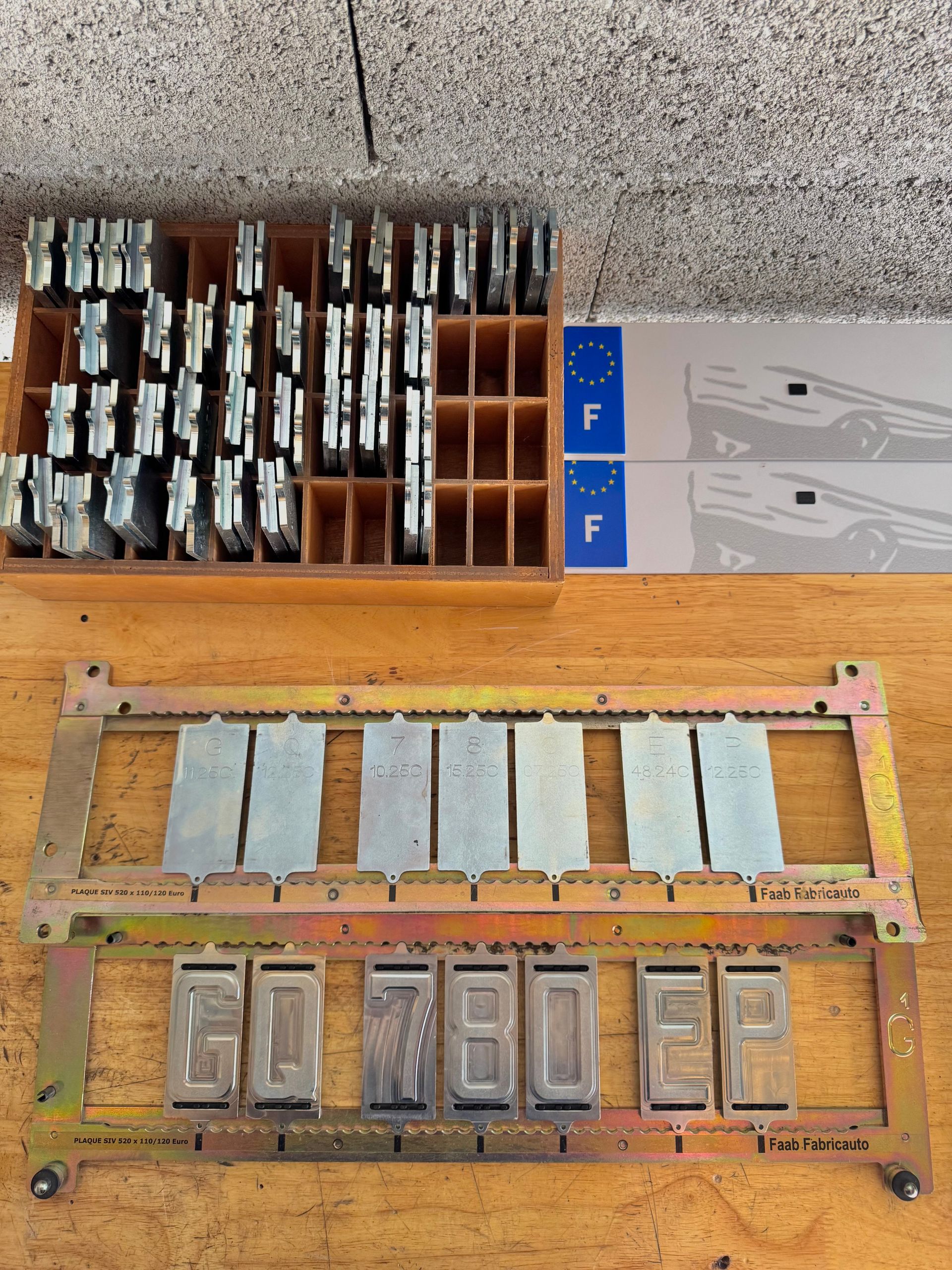 Outils et matériel pour plaques d'immatriculation françaises : tampons, plaques et boîtes de rangement.