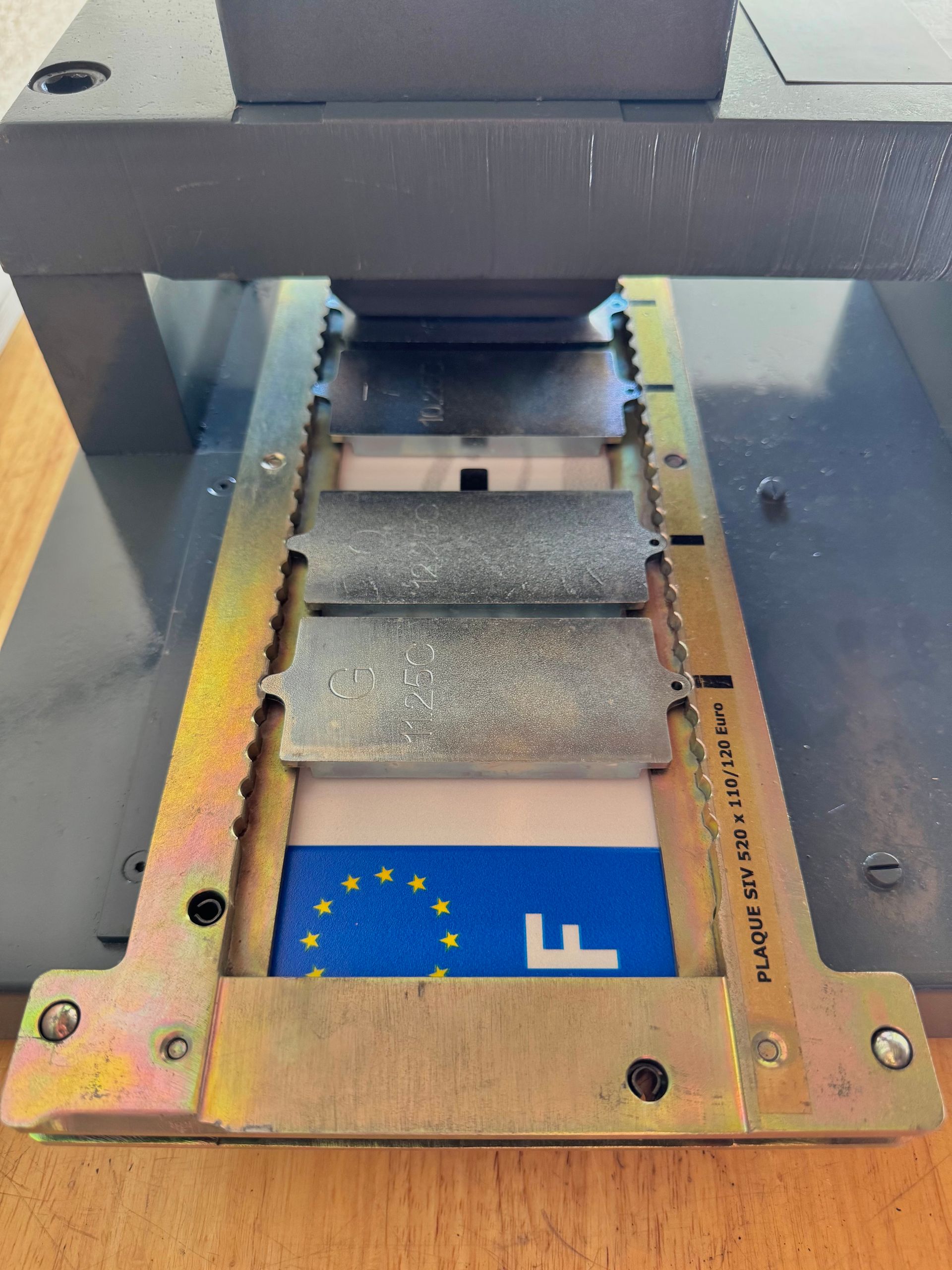 Une presse à métaux serrant une plaque d'immatriculation européenne.