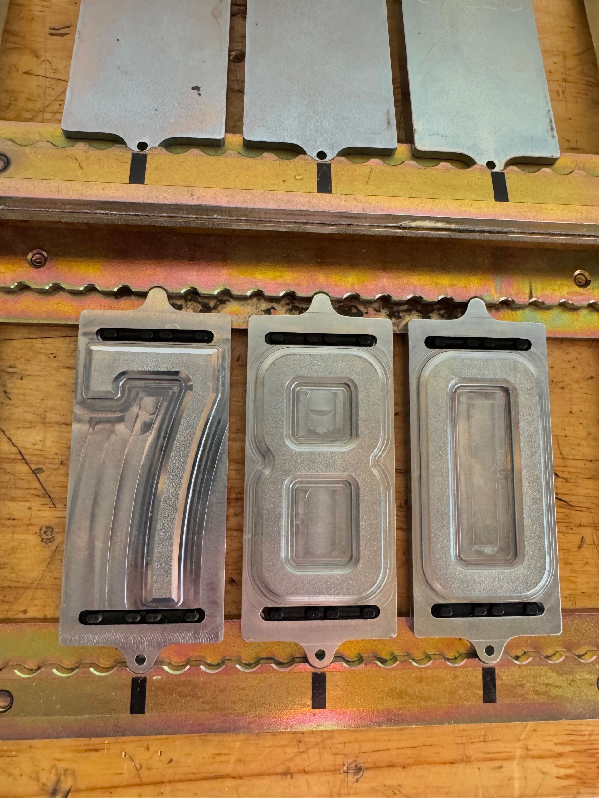 Timbres numériques en métal, « 780 », dans un plateau en bois, avec des plaques vierges correspondantes au-dessus.