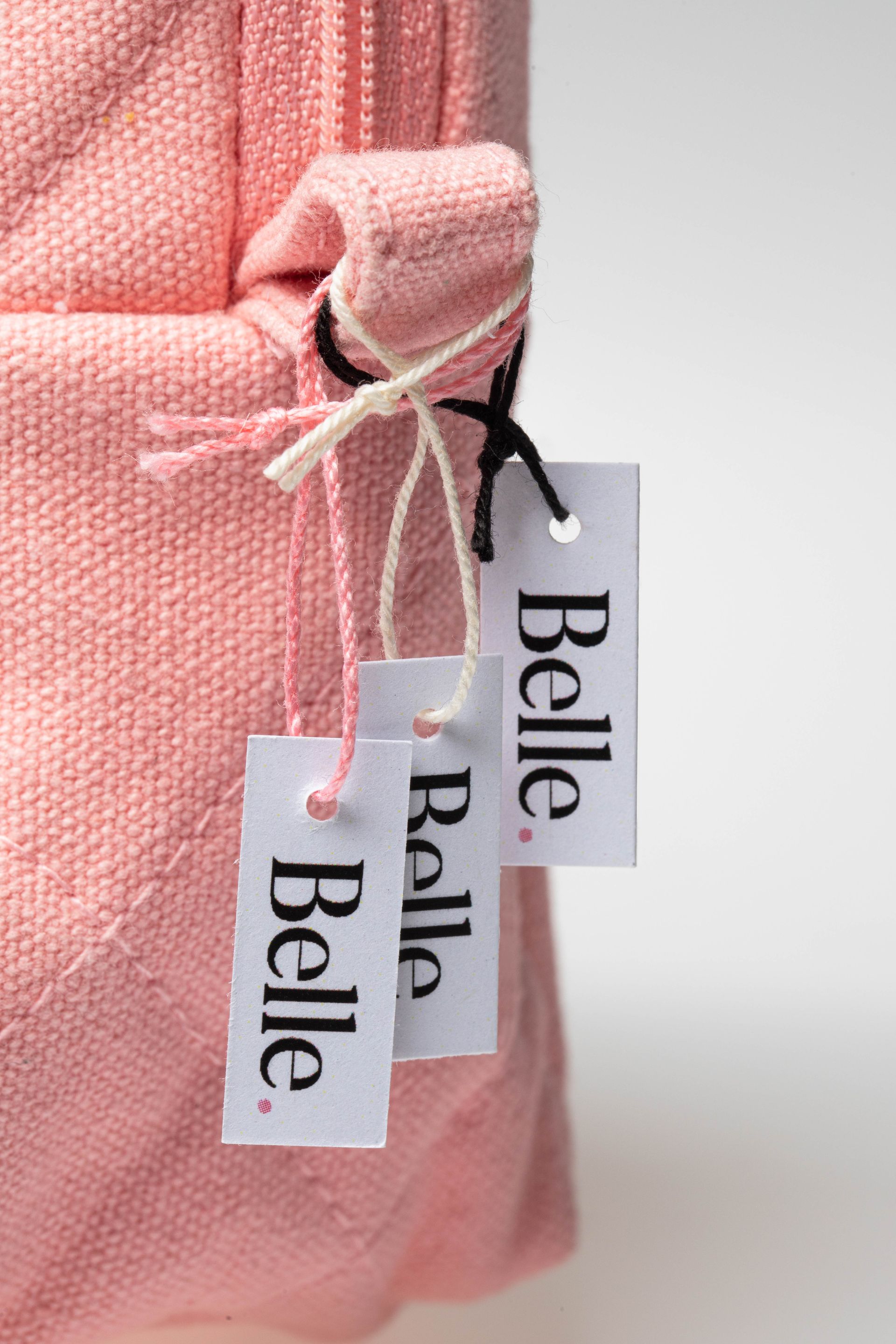 Étiquettes à fil accrochées à un sac en tissu rose.