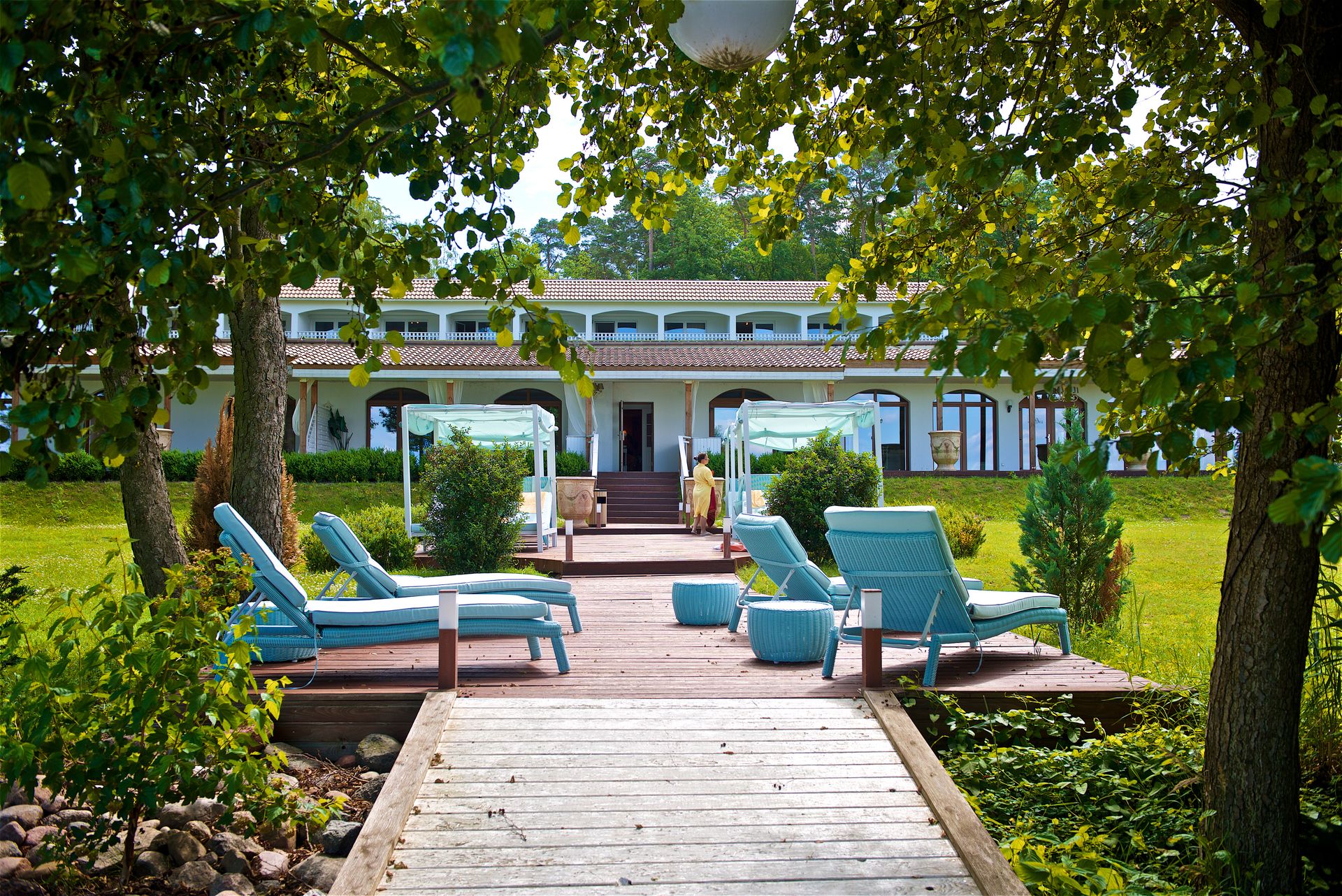 Ein Holzsteg führt zu einem großen weißen Haus