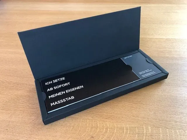 Black box holding a black card with white text that says: