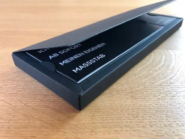 Schwarze Box mit geöffnetem Deckel, in der sich ein Lineal mit der Aufschrift „Ich habe sofort meinen eigenen Maßstab“ befindet.