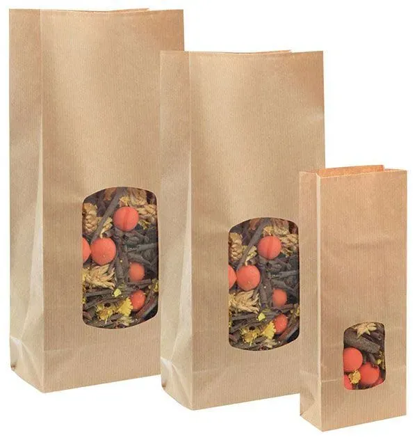 Drei braune Papiertüten mit Fensterausschnitten, in denen jeweils Obst und Blätter zu sehen sind.