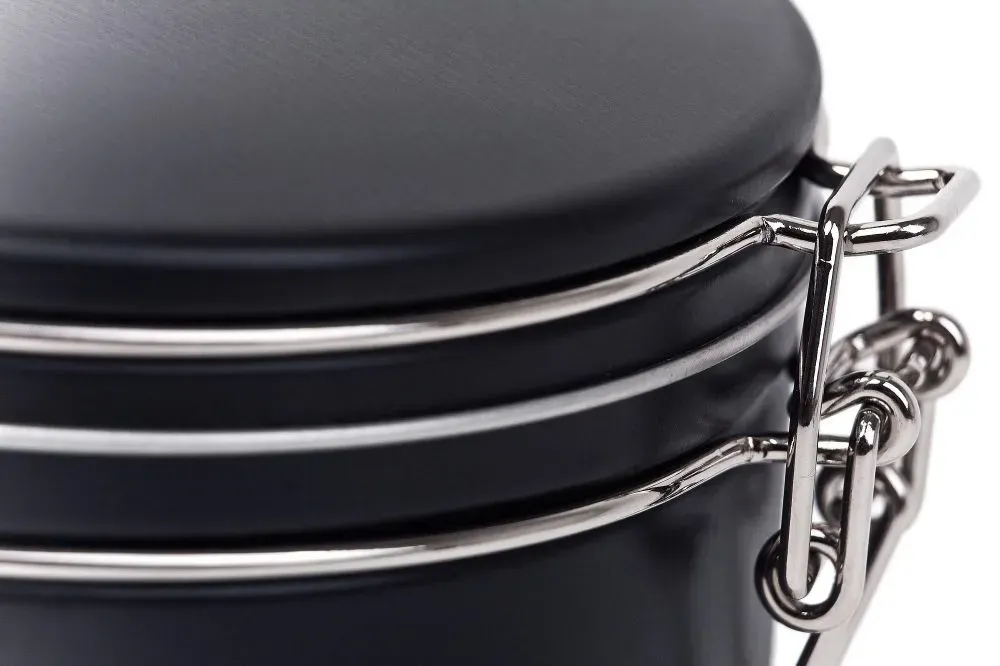 Schwarzer Kanister mit silbernem Metallverschluss und Bändern.