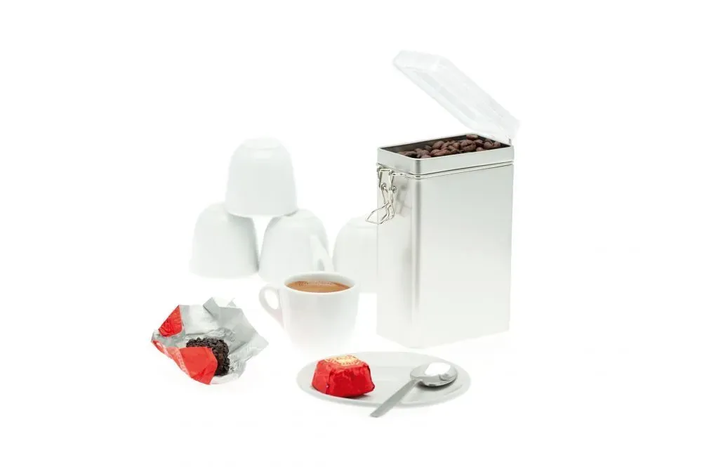 Kaffee und Süßigkeiten: Kaffeetasse, Kuchen, Pralinen und Kaffeebohnen in der Dose.