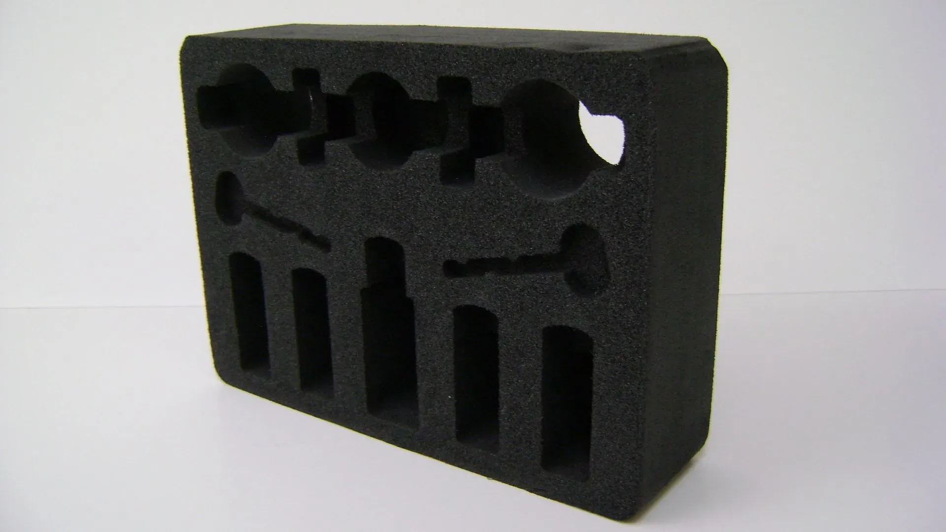 Schwarzer Schaumstoffeinsatz mit ausgeschnittenen Formen zum Ordnen von Werkzeugen oder Komponenten.