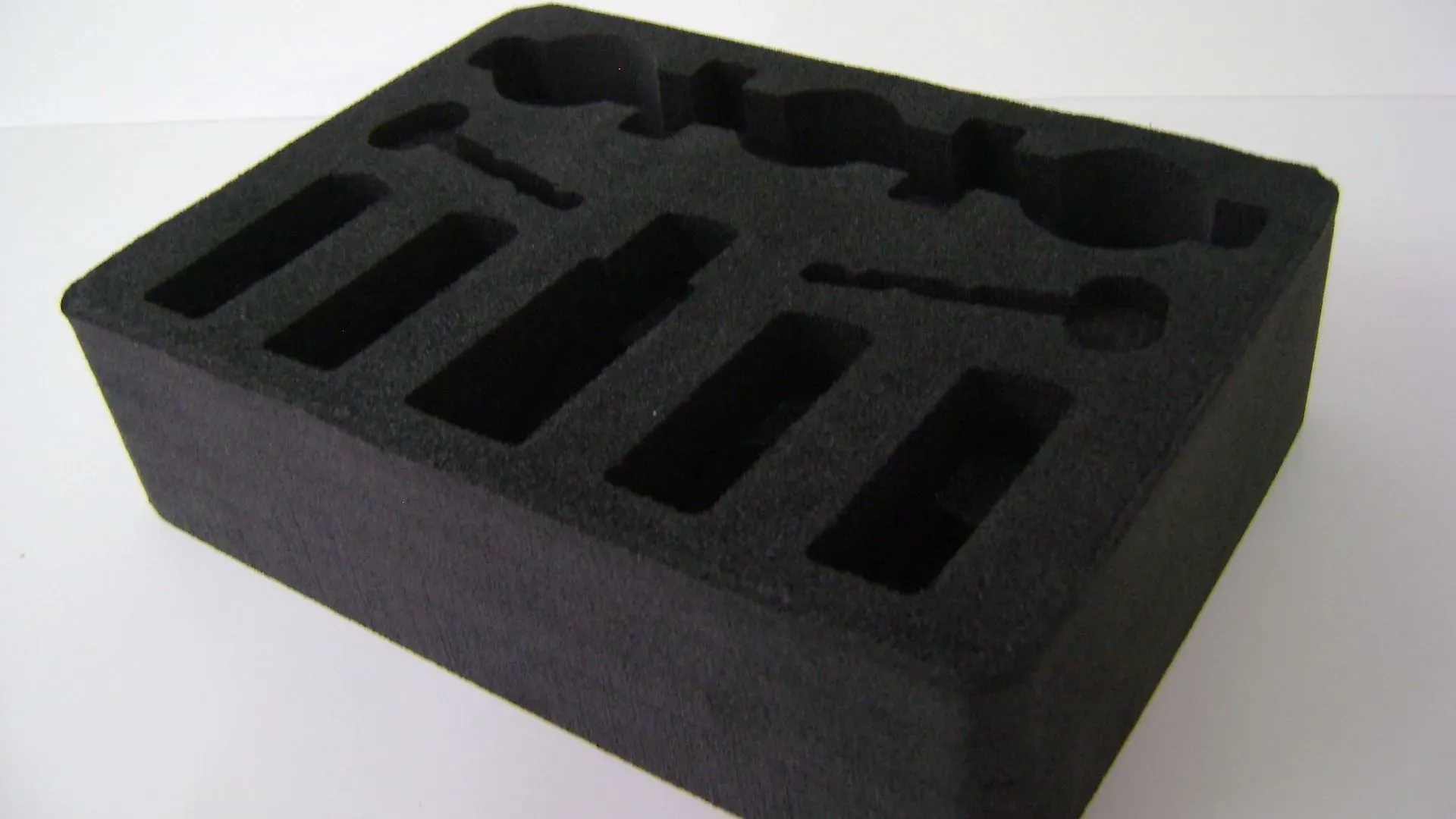 Schwarzer Schaumstoffeinsatz mit individuellen Aussparungen zur Aufnahme verschiedener Werkzeuge und Geräte.