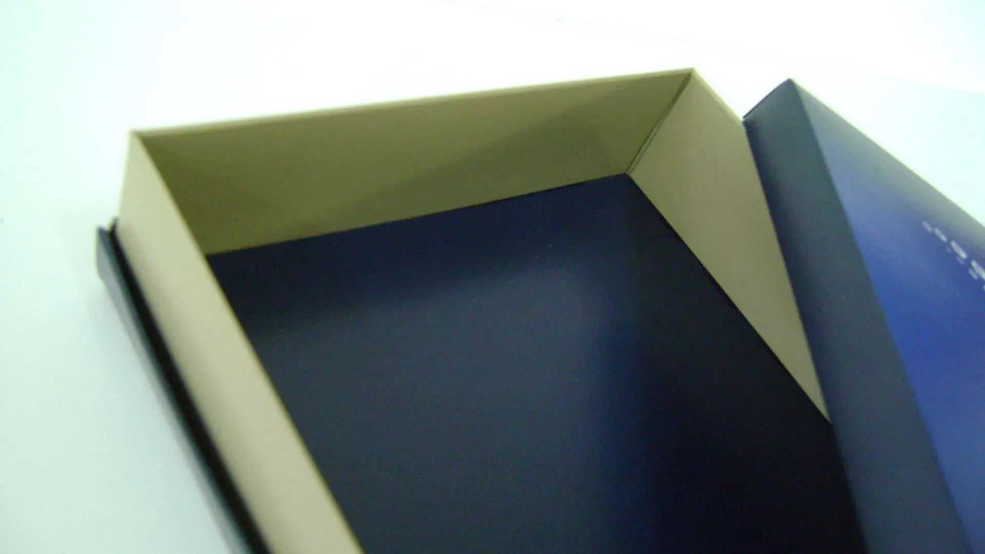 Offene rechteckige Schachtel, innen blau und der Rand hellbraun.