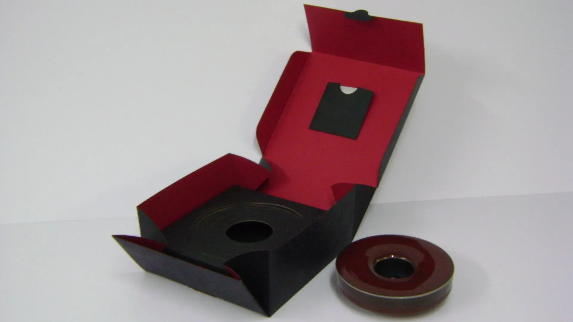 Öffnen Sie eine schwarz-rote Box mit einem braunen, runden Objekt.