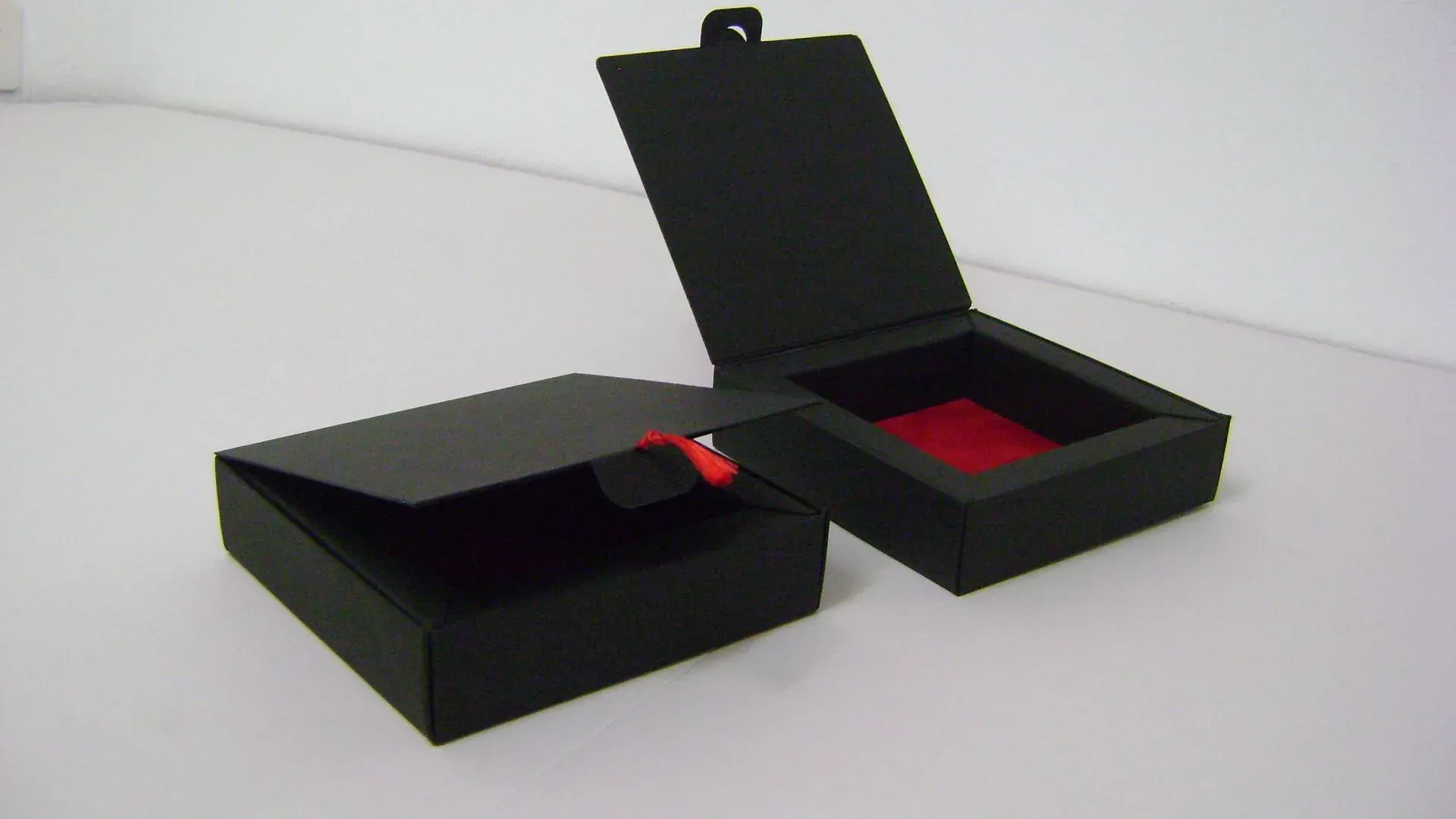 Schwarze Schmuckschatullen, eine geschlossen, eine offen mit rotem Innenleben.