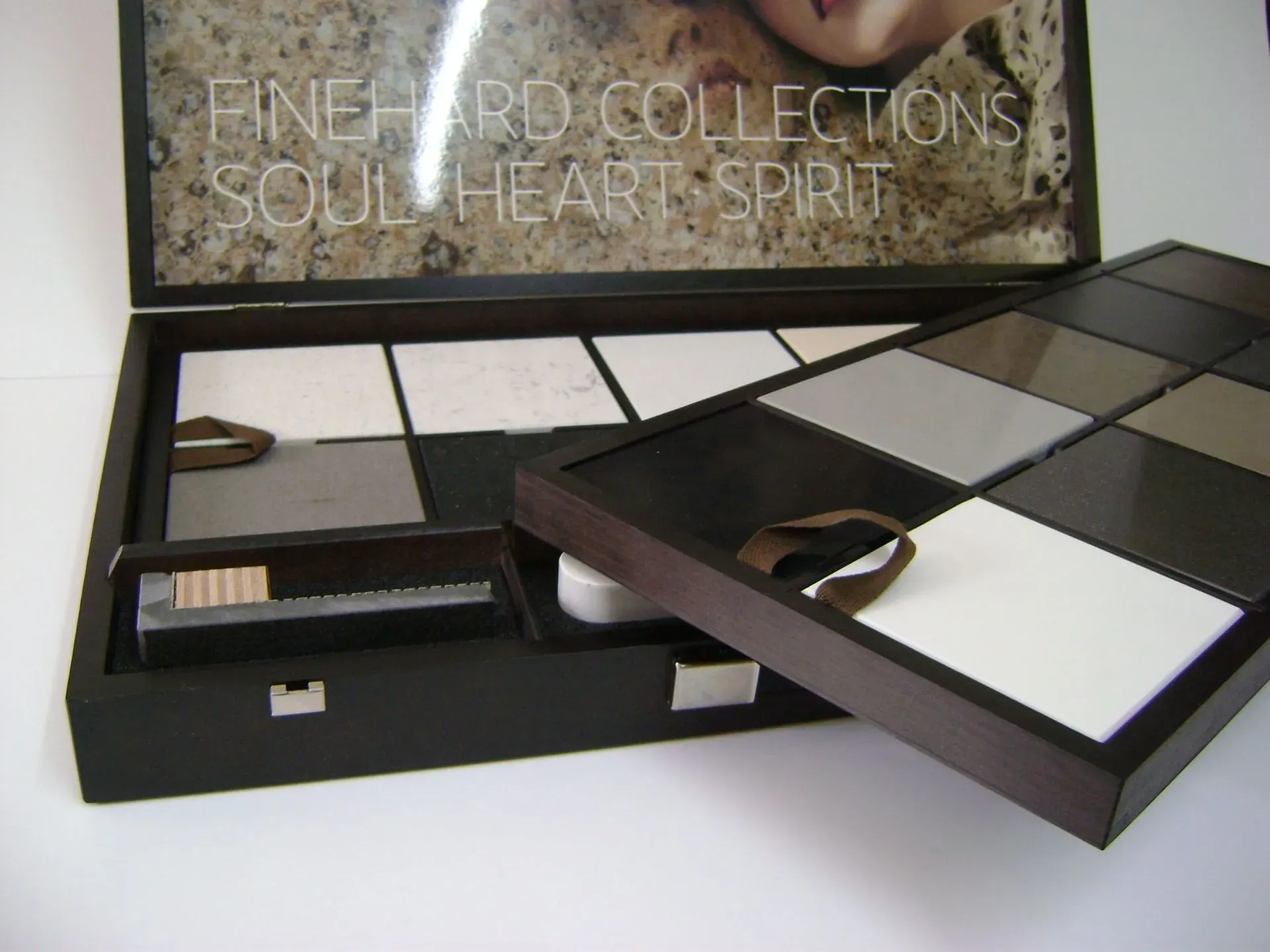 Vitrine mit Fliesenmustern in verschiedenen Grau- und Weißtönen. Text „Fine Hard Collections“ sichtbar.