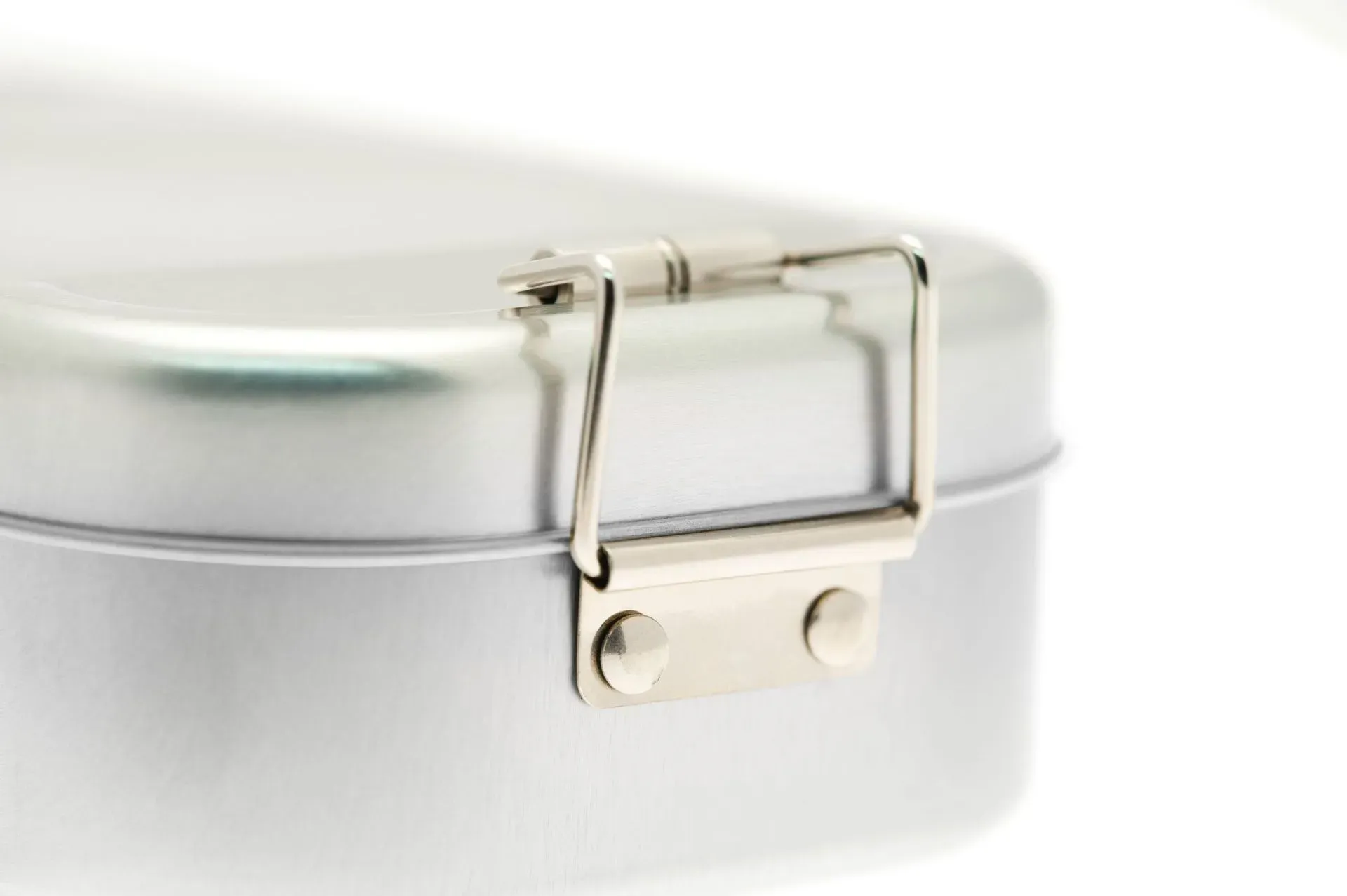 Nahaufnahme einer silbernen Lunchbox aus Metall mit Klappverschluss vor weißem Hintergrund.