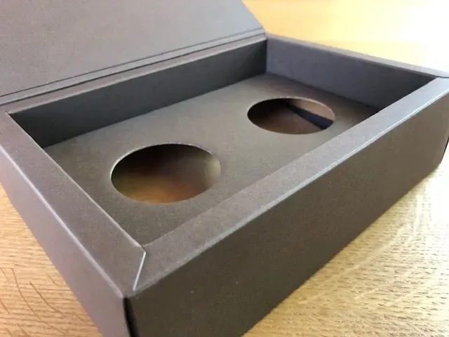 Offene schwarze Box mit zwei kreisförmigen Ausschnitten.