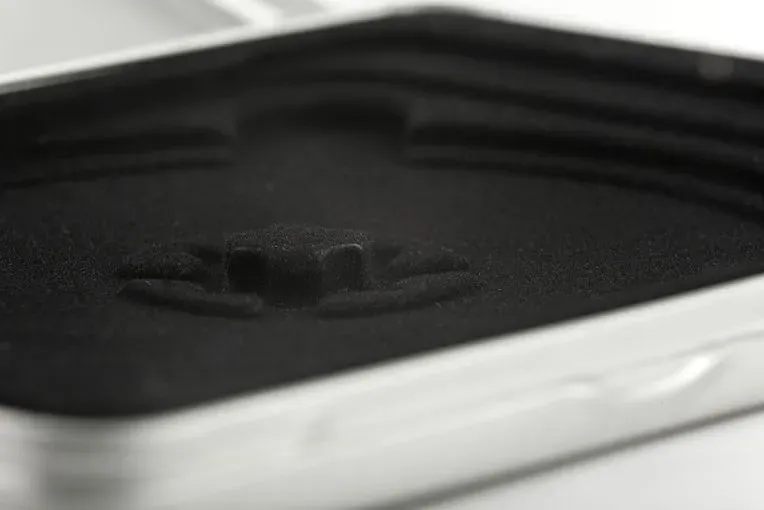 Nahaufnahme einer offenen, leeren Make-up-Dose mit mattschwarzer Oberfläche und silbernem Rahmen.