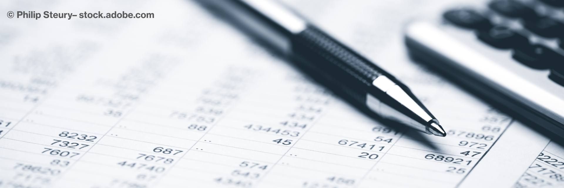 Papier mit Tabelle und vielen Zahlen, darauf ein Stift und Taschenrechner