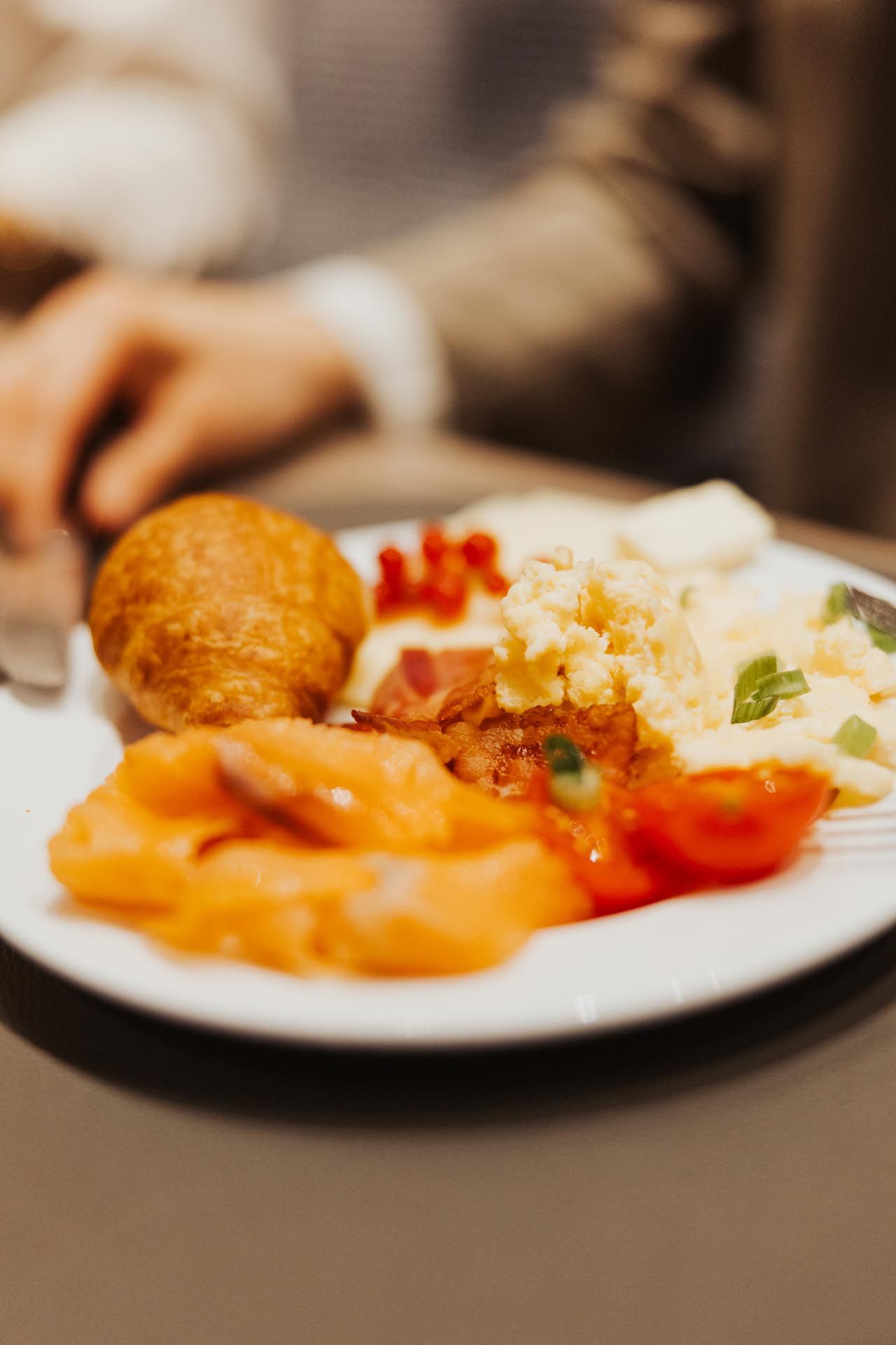 Ein Tellergericht mit Lachs, Kartoffelpüree, Garnelen und einer panierten Kroketten auf einem Esstisch