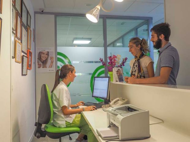Un hombre y una mujer están de pie frente a un mostrador en un consultorio dental.