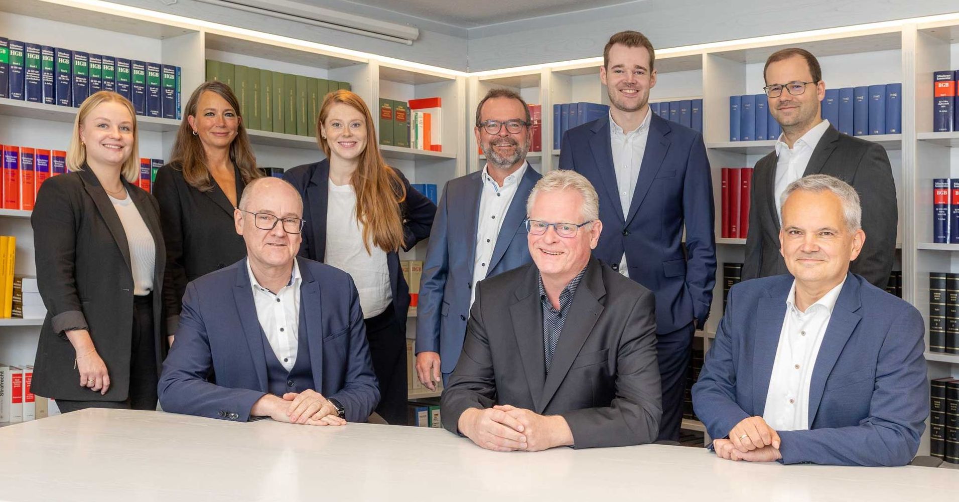 Gruppe von Anwälten in Anzügen posiert in einem Büro.