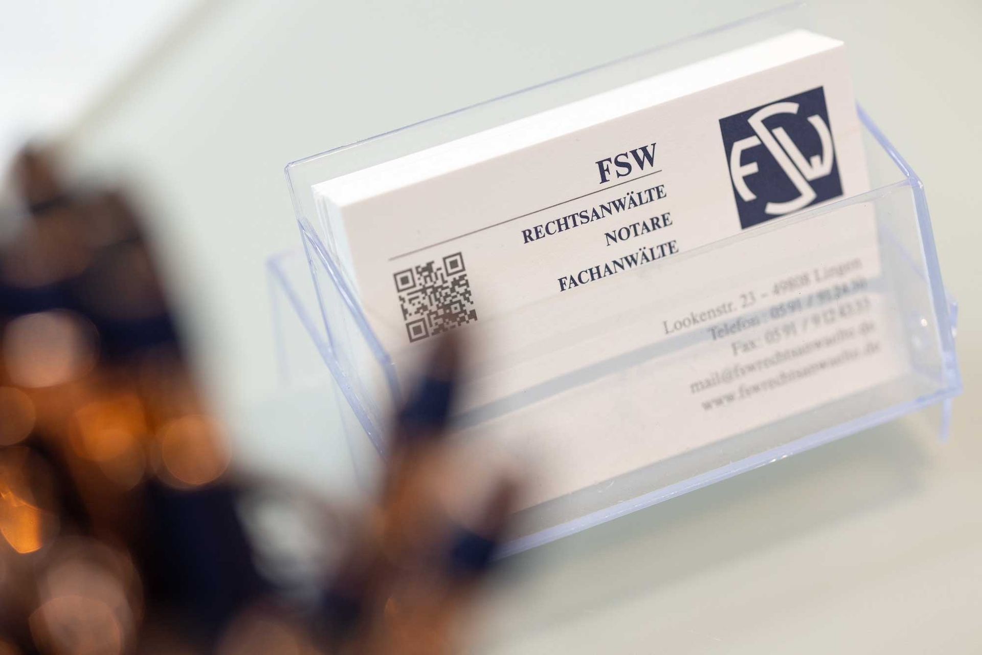 Visitenkarten im Klarsichthalter, mit dem Logo „FSW“ und Kontaktdaten.