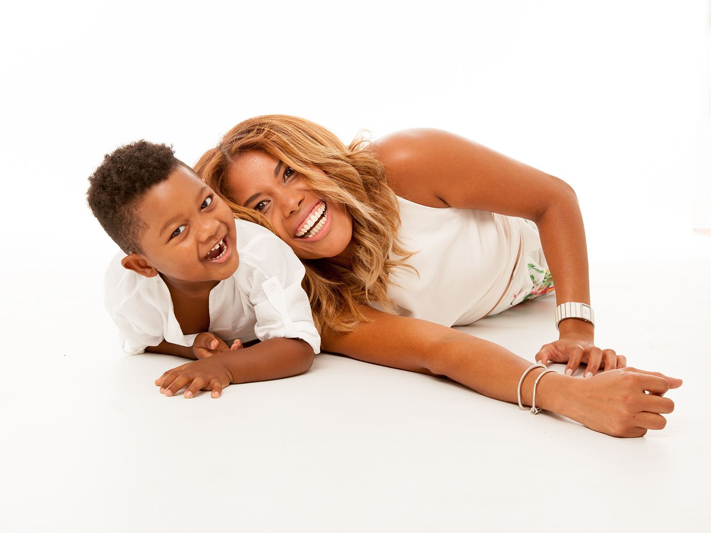 Mujer y niño acostados, riendo. Fondo blanco.