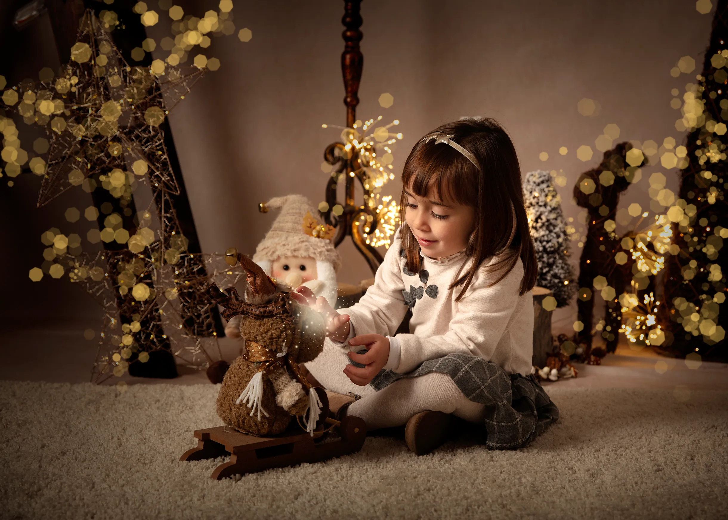 Una niña sonríe mientras interactúa con un muñeco de nieve decorativo. Luces y adornos navideños al fondo.