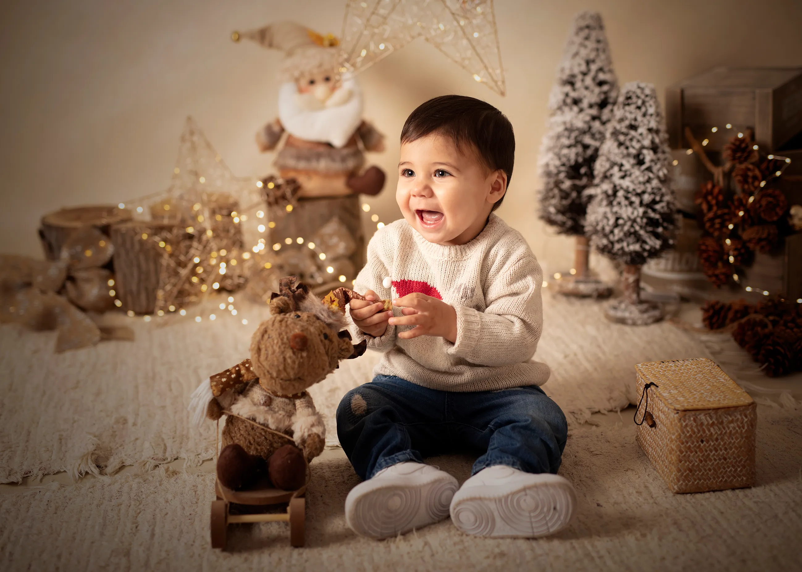 Niño pequeño feliz en un ambiente navideño, sosteniendo un juguete, sonriendo y rodeado de decoraciones.