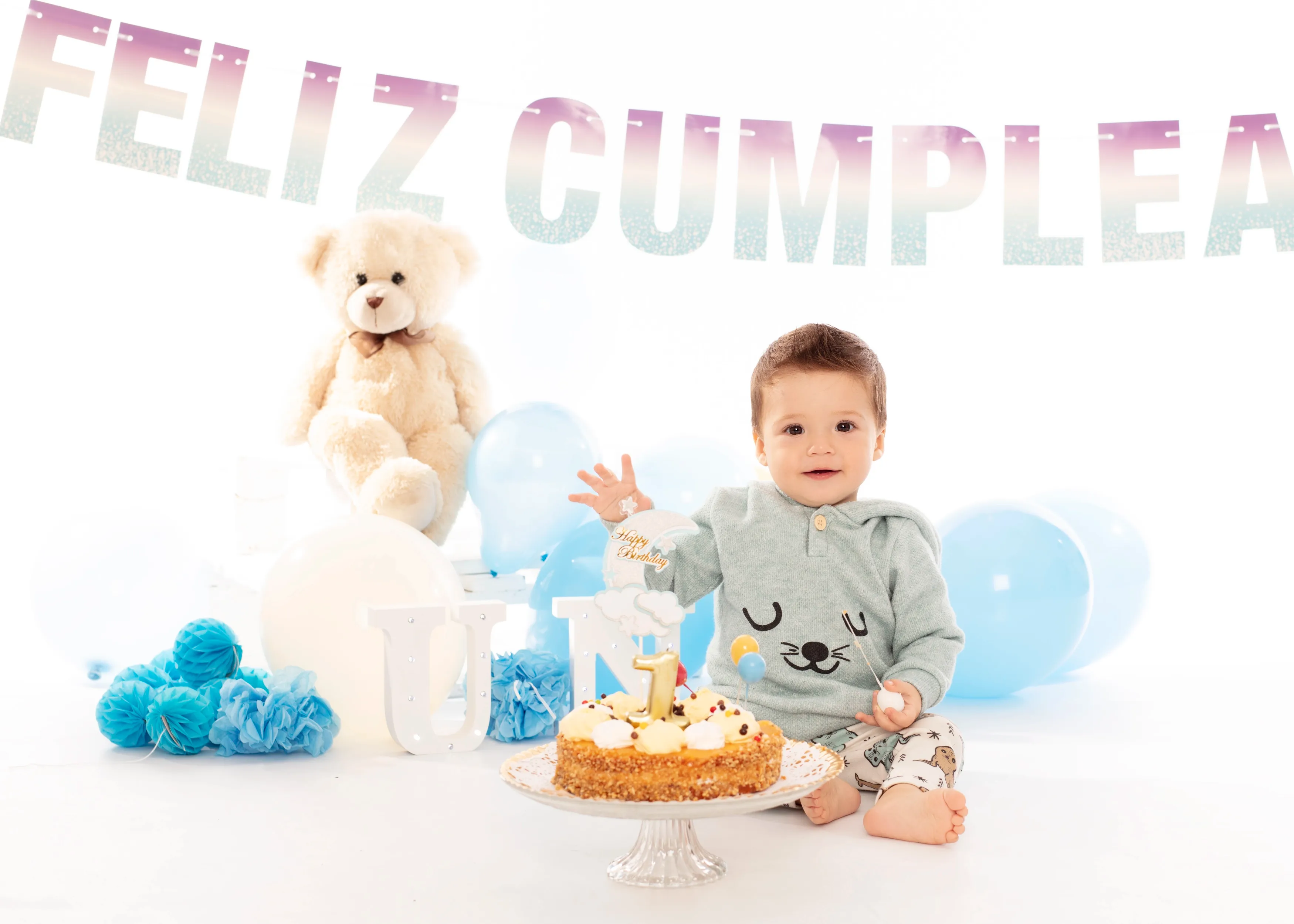Bebé celebrando su primer cumpleaños con pastel, globos y pancarta de 