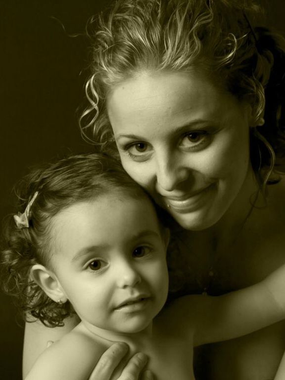 Mujer y niño pequeño abrazados, ambos mirando hacia la cámara, tono sepia.