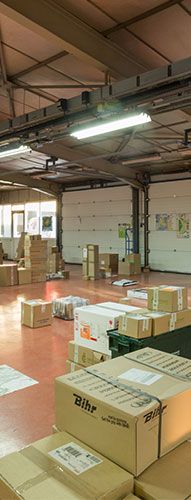 Entrepôt avec des cartons empilés sur un sol en béton sous des néons