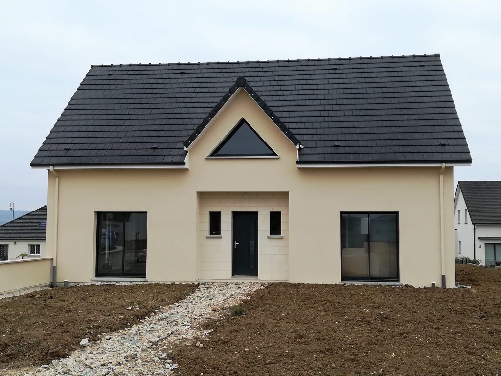 Maison couleur crème avec fenêtre d'étage centrale triangulaire