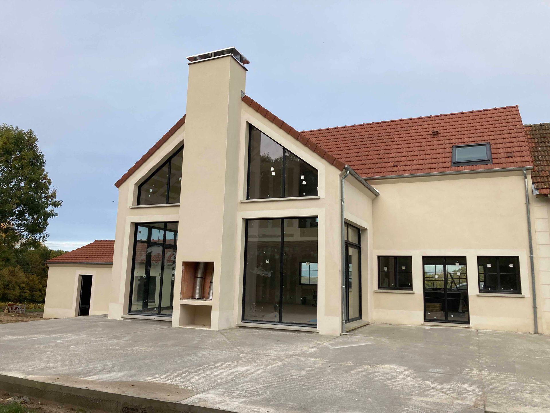Extérieur d'une extension de maison moderne avec portes coulissantes à cadre sombre.