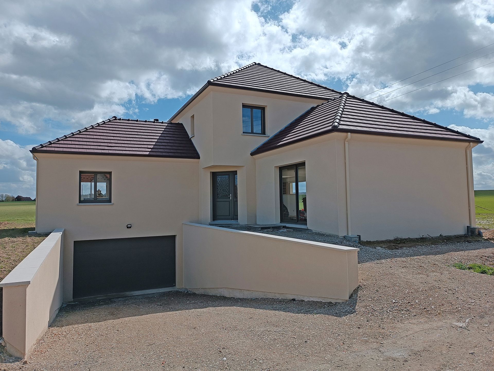 Maison couleur crème avec fenêtre d'étage centrale triangulaire