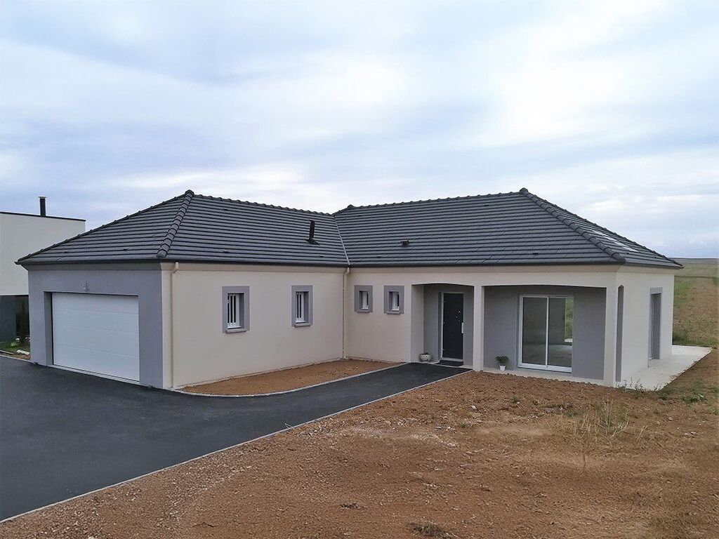 Une maison moderne de plain-pied avec des murs gris et beiges, un toit foncé et une allée asphaltée.
