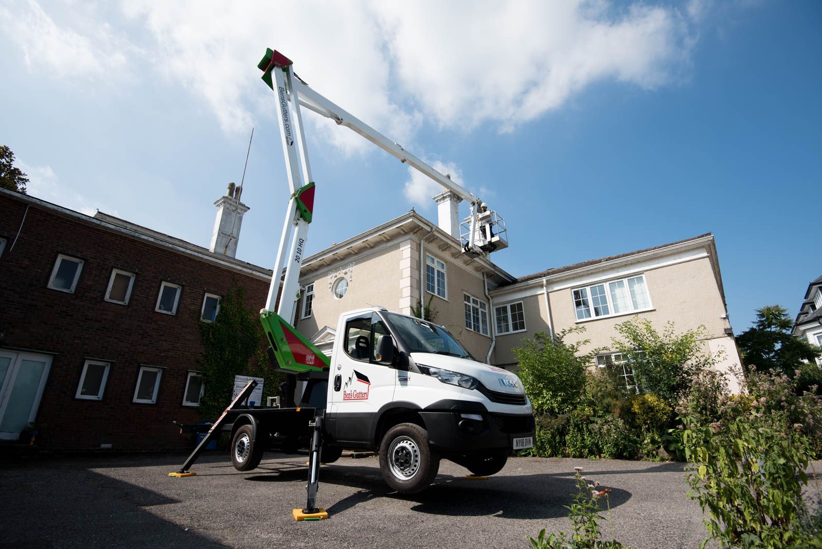 White crane truck lifting equipment beside a building under a blue sky