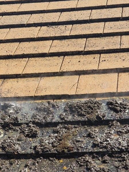 Close-up of a sloped, yellow roof with dark shadow lines and a rough stone edge at the bottom