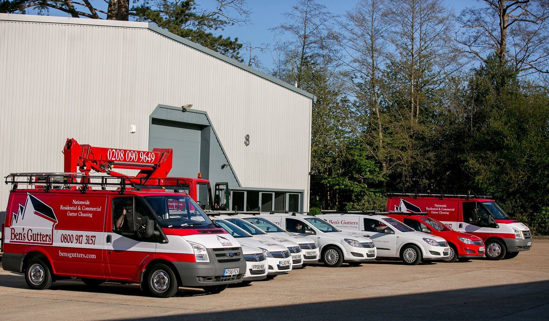 Tow trucks and service vans parked outside a white industrial building