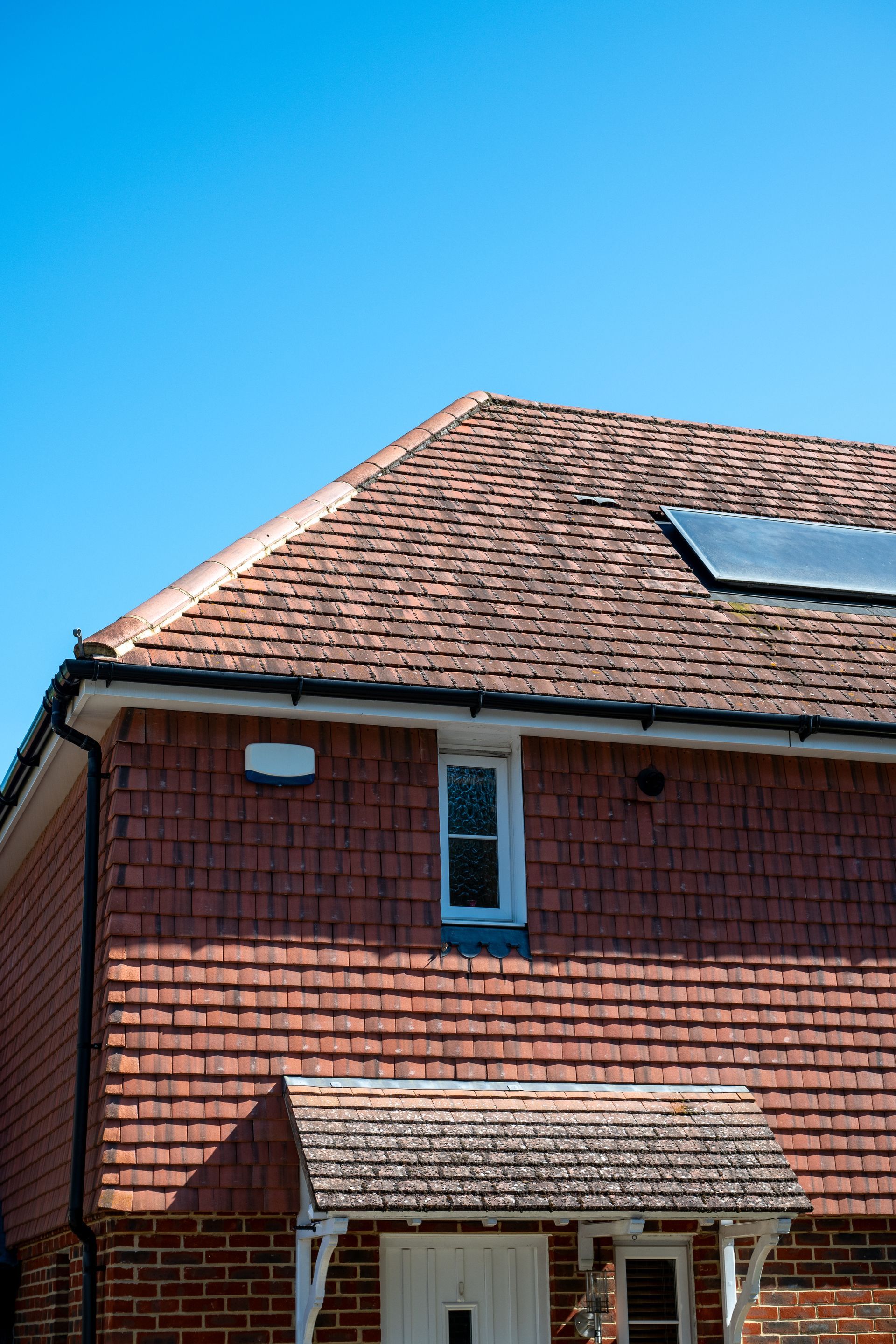 Red house with tiled roof and skylight under a clear blue sky