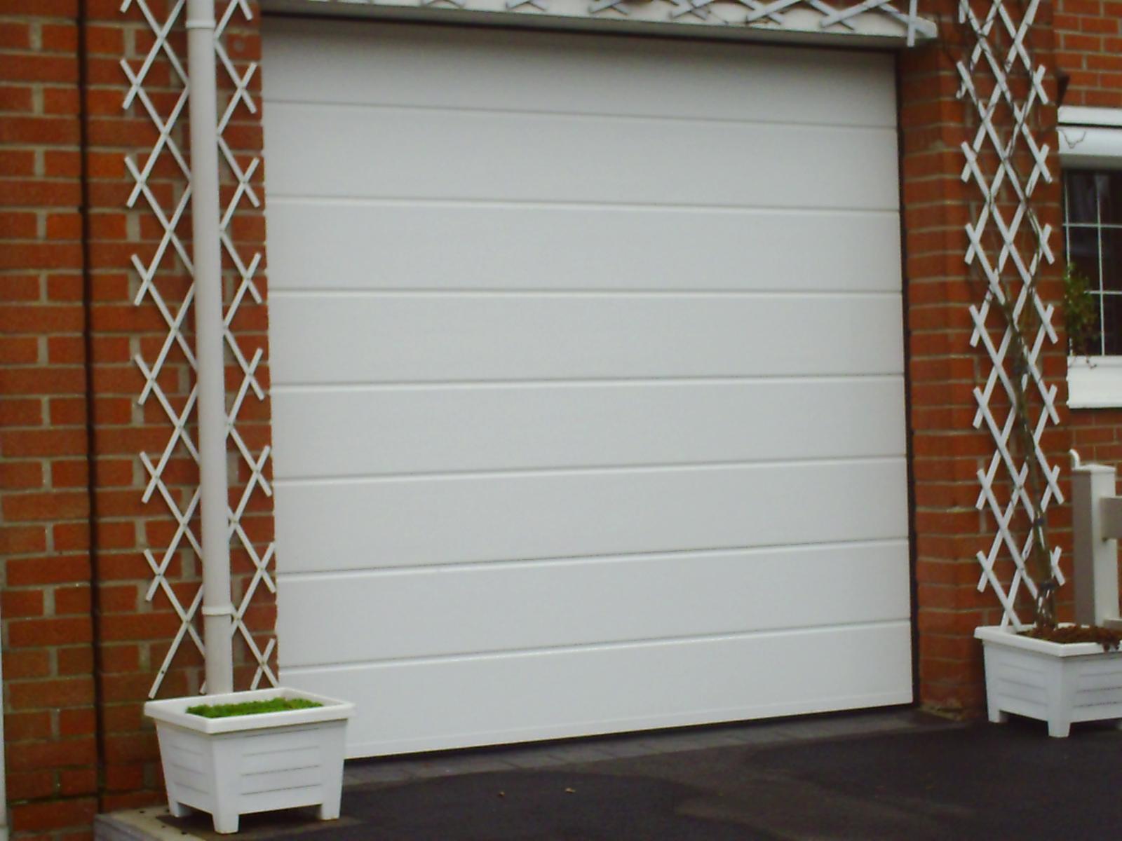 Porte de garage blanche avec pots de fleurs et treilles