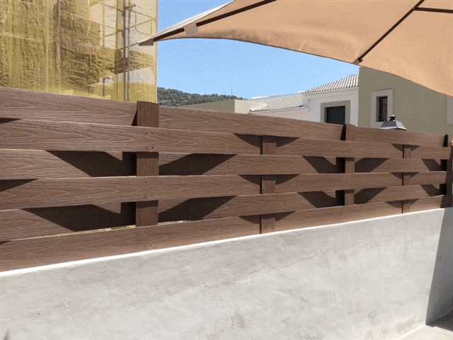 Un paraguas marrón está debajo de una valla de madera.