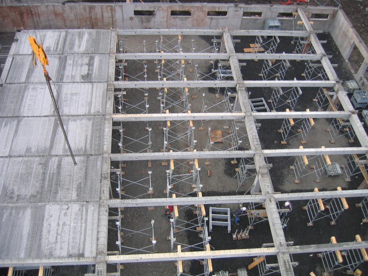 Vue aérienne d'un chantier de construction en béton avec poutres, supports et panneaux gris.