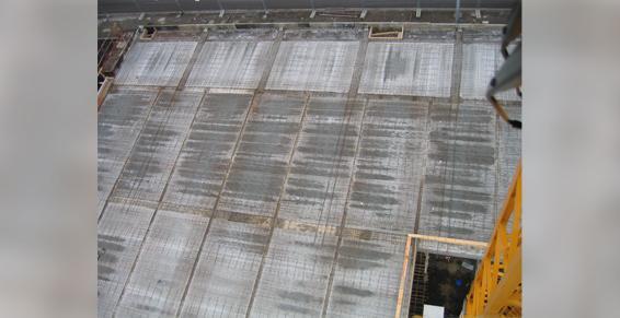 Vue aérienne d'un chantier de construction en béton comportant plusieurs sections rectangulaires, certaines avec des grilles métalliques intégrées.