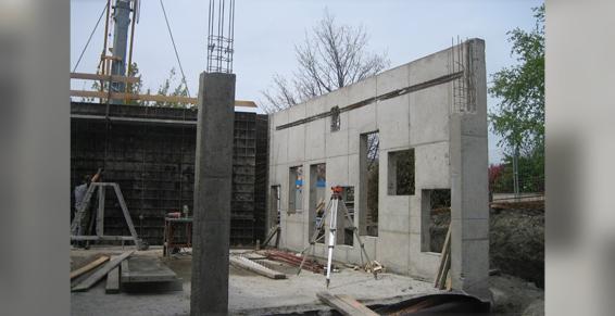 Mur en béton en construction avec ouvertures pour fenêtres ; support vertical en béton.